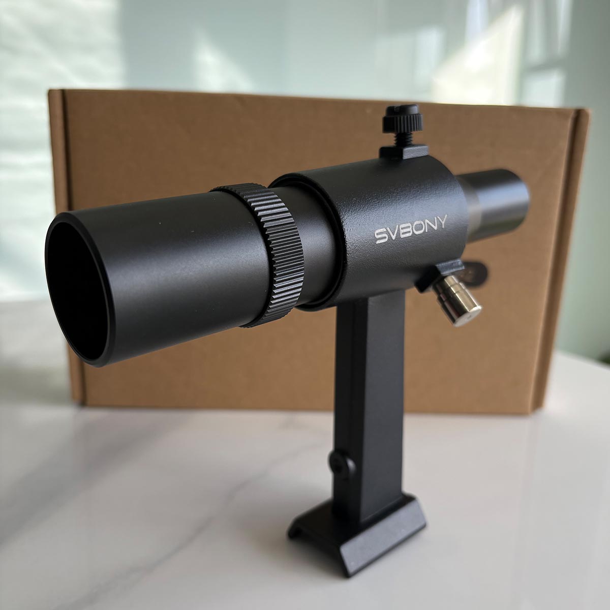 SV182 6x30 Finder Scope with 'Svbony' branding on a white surface with a cardboard box in the background.